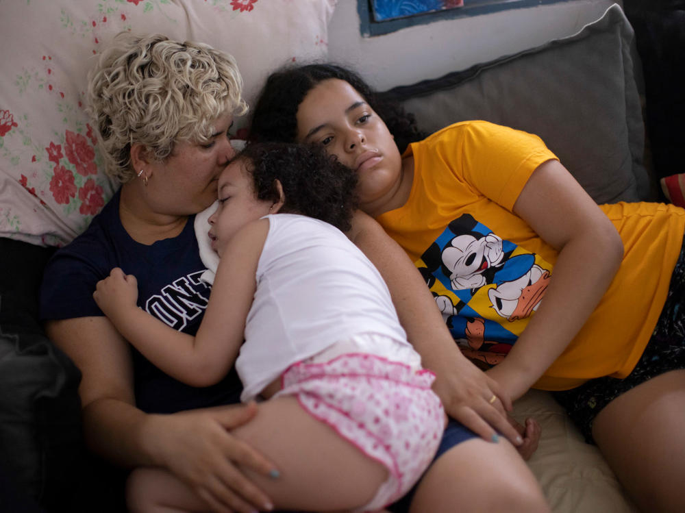 Dos Santos, left, with her daughters. Dos Santos says she feels used and that many other families share the same sentiment. Medical anthropologist Luciana Lira says the families became overwhelmed by scientists and journalists, and that she had to change her approach to gain the families' trust.