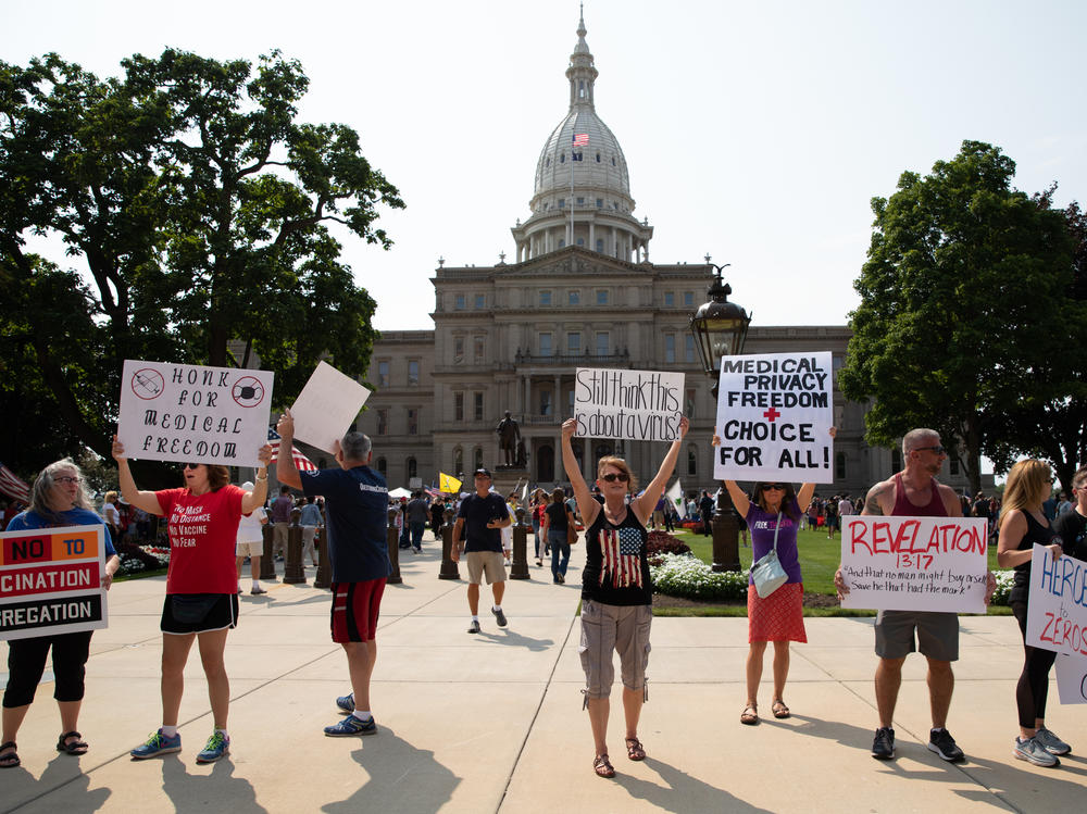 A group of demonstrators hold signs as they protest against mandated vaccines outside the Michigan State Capitol on Aug. 6, 2021 in Lansing, Michigan.