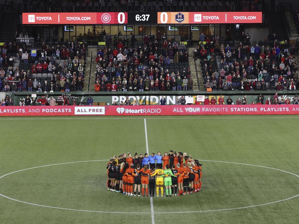 Portland Thorns and Houston Dash players, along with referees, gather at midfield, in demonstration of solidarity with two former NWSL players who came forward with allegations of sexual harassment and misconduct against a prominent coach, during an NWSL soccer match in Portland, Ore., Oct. 6, 2021.
