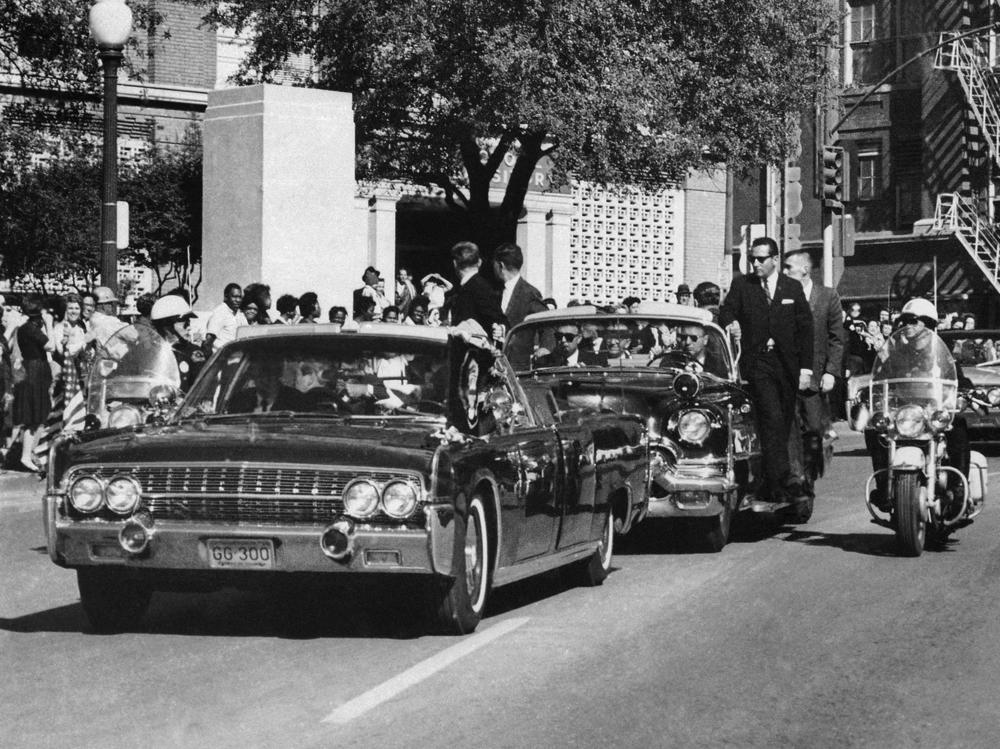 In this Nov. 22, 1963, file photo, seen through the foreground convertible's windshield, President John F. Kennedy's hand reaches toward his head within seconds of being fatally shot. About 90% of the government records surrounding the assassination have been released but the release of the remaining records have now been delayed.