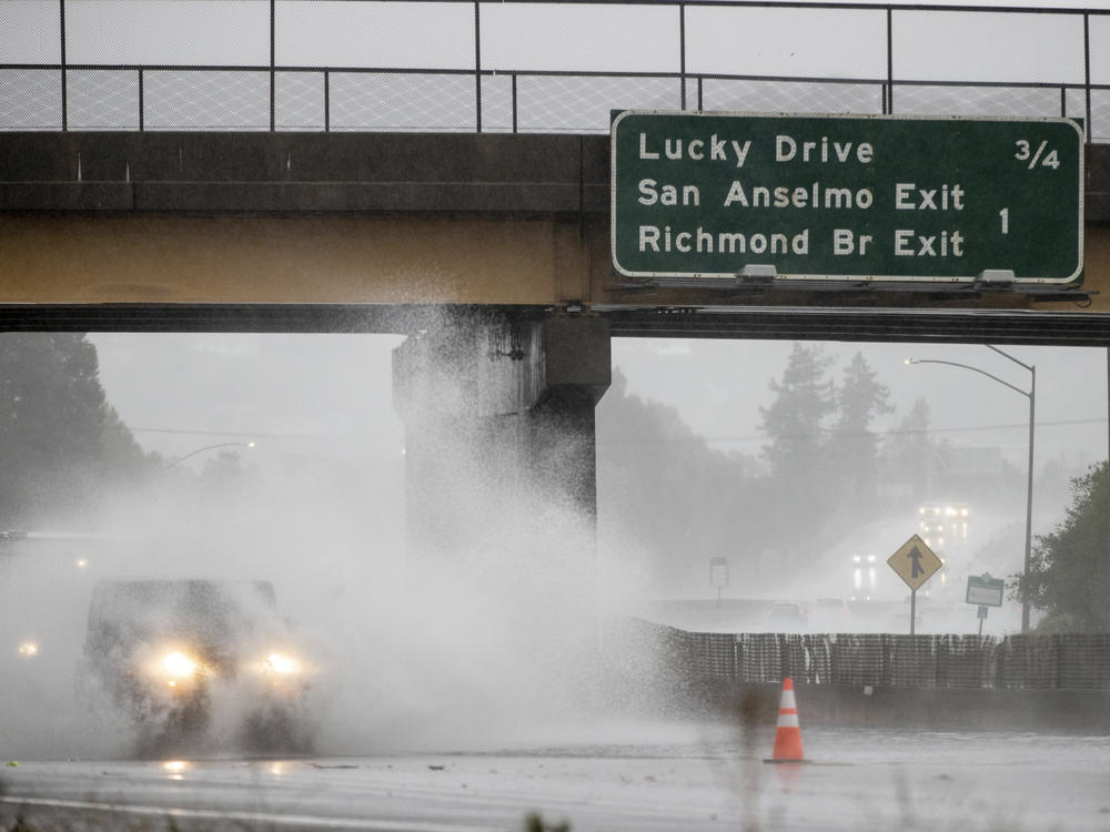 A car drives on Highway 101 Sunday, which is partially flooded in Corte Madera, Calif..