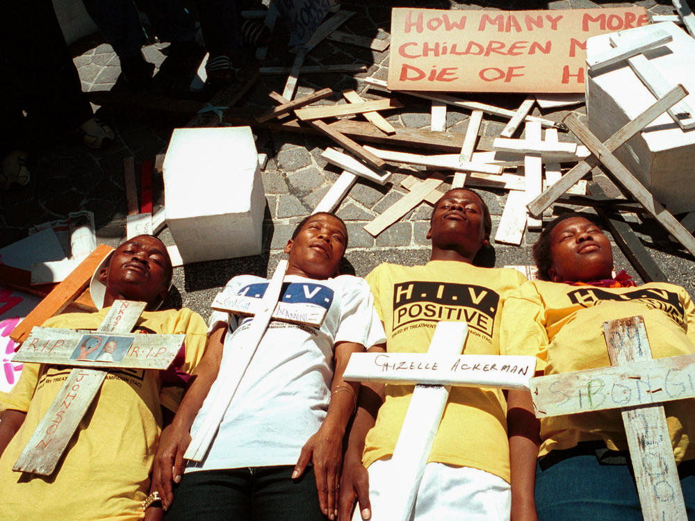 Four youths lay on the ground surrounded by crosses symbolizing victims of HIV-AIDS in a demonstration on November 26, 2001 in Cape Town, South Africa. The protest was aimed at the government's AIDS policies, including a failure to distribute antiretroviral drugs to pregnant mothers.