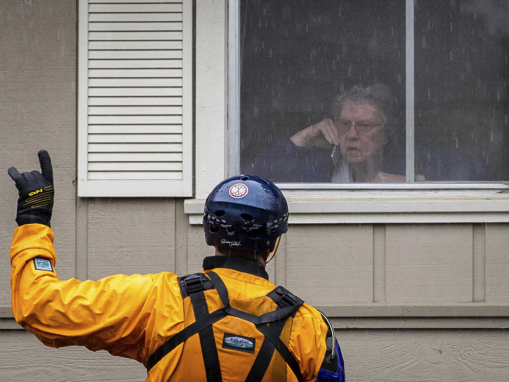 A Santa Rosa firefighter convinces a resident to evacuate after being trapped by floodwaters on Neotomas Ave. in Santa Rosa, Calif., Sunday.