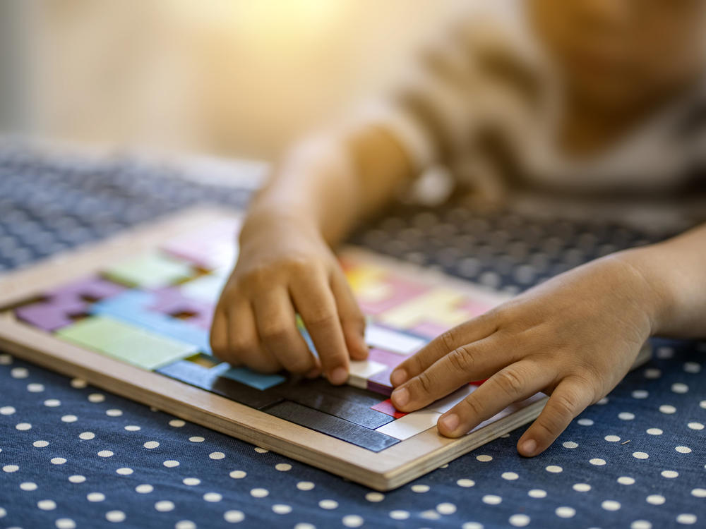 A child plays with colorful plastic blocks. Children in need of quality childcare is in high demand but short supply, including for disabled children,  parents say.