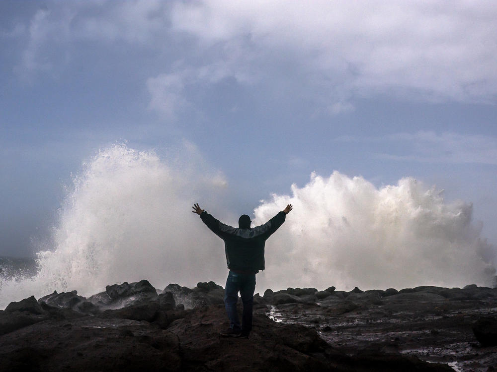 A man reacts as large waves caused by a bomb cyclone storm system break against the Oregon coast Sunday in Depoe Bay, Oregon. Heavy rain and wind may cause flooding in some parts of the region, but could aid areas of California struggling with wildfires.