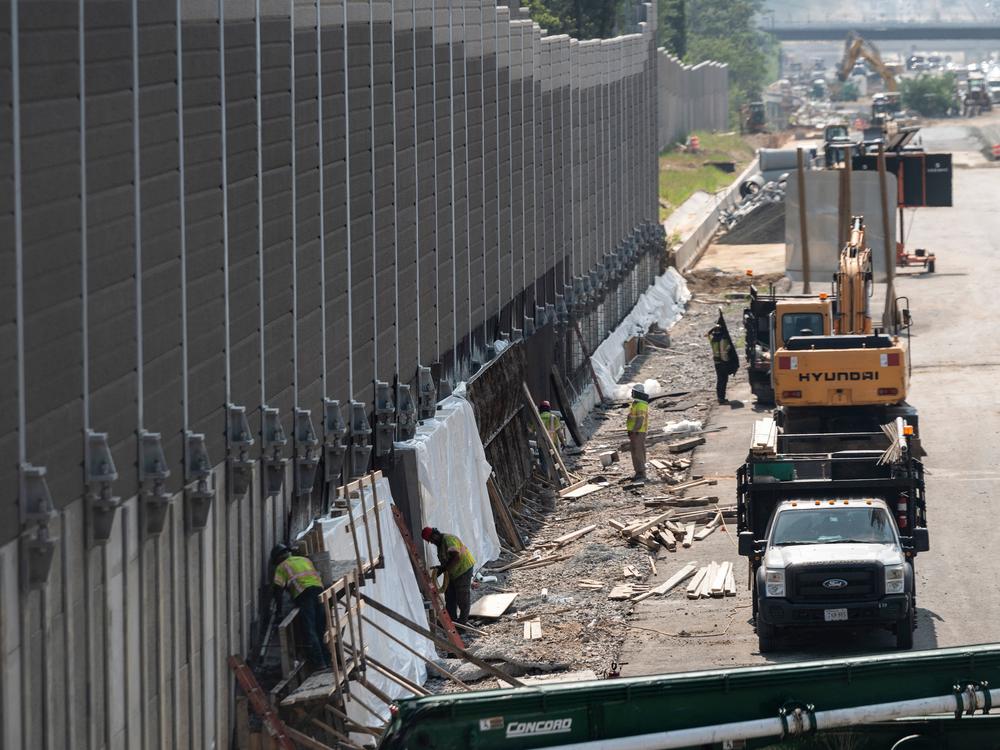 Construction workers build a sound wall along Interstate Highway 66 in Fairfax, Va., this past August. While Congress debates President Biden's infrastructure bill, some rural transportation projects are in limbo.