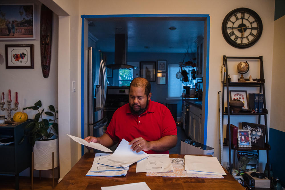 Michael Dew sits in his dining room looking through property records related to his home in San Diego's El Cerrito neighborhood.