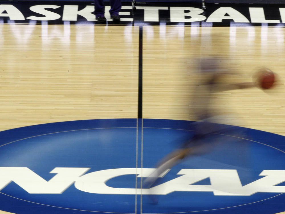 A player streaks across the NCAA logo at midcourt during basketball practice in this file photo from March 14, 2012.
