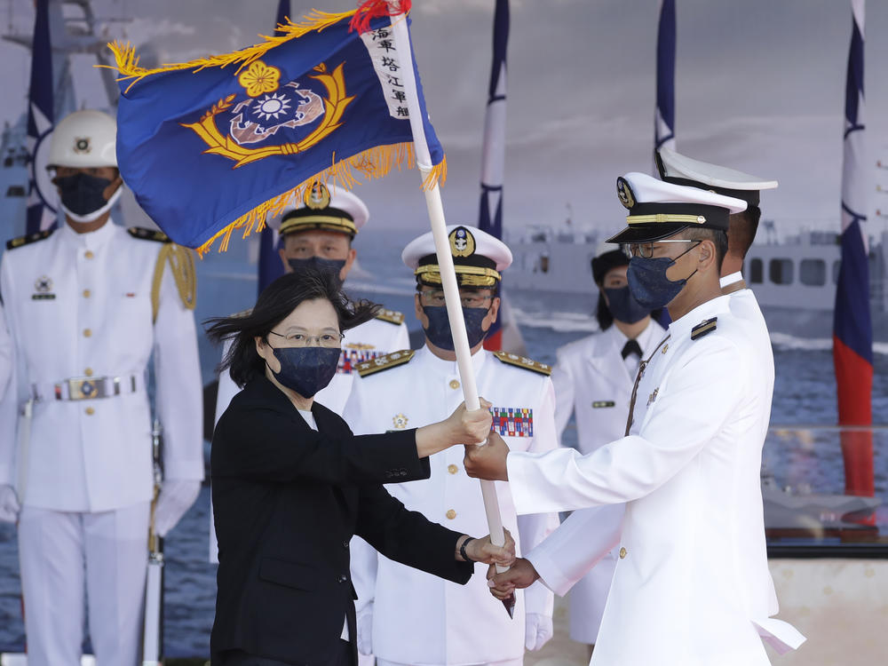 Taiwan's President Tsai Ing-wen (left) presents a flag during the commissioning ceremony of the a domestically made warship at the Suao Naval Base in Yilan county, Taiwan, on Sept. 9. Taiwan's president oversaw the commissioning of the new ship as part of the island's plan to boost its defense capacity amid heightened tensions with China.