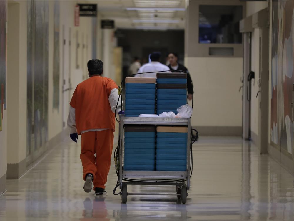 A detainee worker moves a cart of trays containing chicken fajita meals during a 2019 media tour of the U.S. Immigration and Customs Enforcement detention center in Tacoma, Wash.