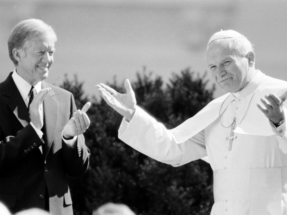 Pope John Paul II acknowledges applause from President Jimmy Carter and other dignitaries as the pontiff is welcomed to the White House on Oct. 6, 1979.