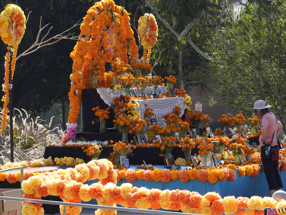 People visit a community altar decorated with marigolds at Grand Park in Los Angeles. Mother and daughter Chicana artists Ofelia and Rosanna Esparza have overseen the design of the altar at Grand Park since 2013. It's one of 11 huge altars done in a collaboration between Grand Park and Self Help Graphics, an organization highlighting Chicano and Latino artists and social justice.