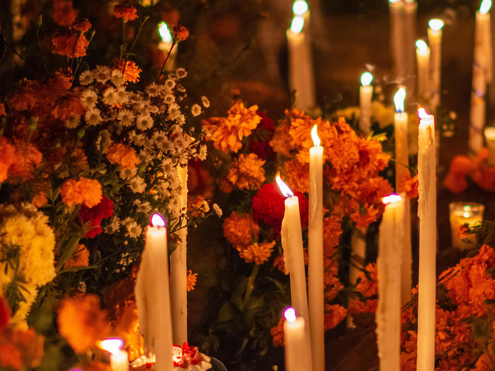 This image depicts how Día de los Muertos is observed and celebrated. Deceased individuals are remembered with the placement of flowers and candles at their cemeteries.