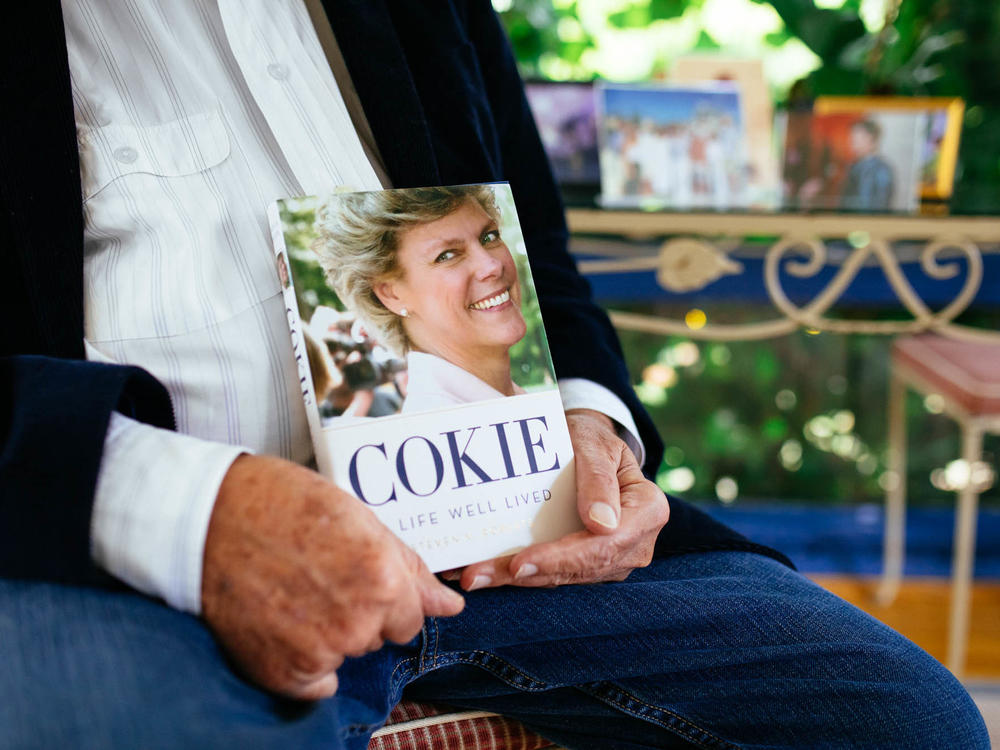 Steven Roberts holds a copy of his book <em>Cokie: A Life Well Lived</em> at his home in Bethesda, Md. The process of writing that book, he says, has helped him feel like he gets to spend more time with his wife.