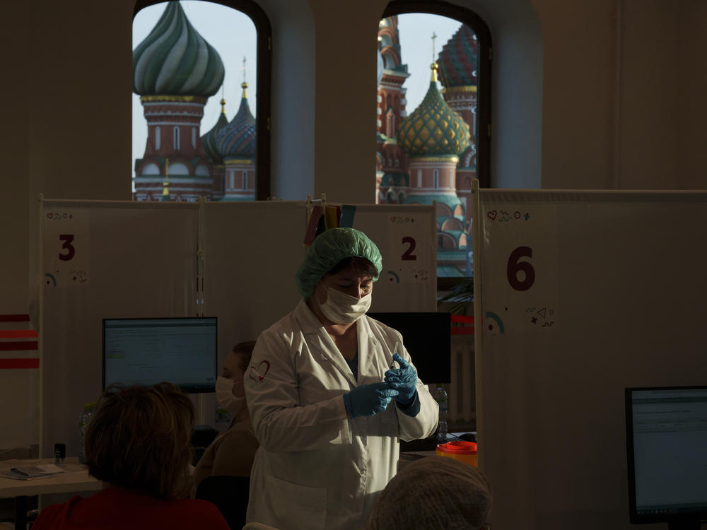 A medical worker prepares a shot of Russia's Sputnik Lite coronavirus vaccine at a vaccination center last week in Moscow's GUM department store in Red Square with the St. Basil Cathedral in the background. The global death toll from COVID-19 has topped 5 million.