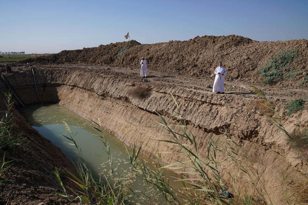 Farmers stand beside a home-dug well in Diyala, Iraq. A prolonged drought has dried up lakes and brought rivers to such low levels that a government spokesperson says the country can cultivate only about half the land it normally would.