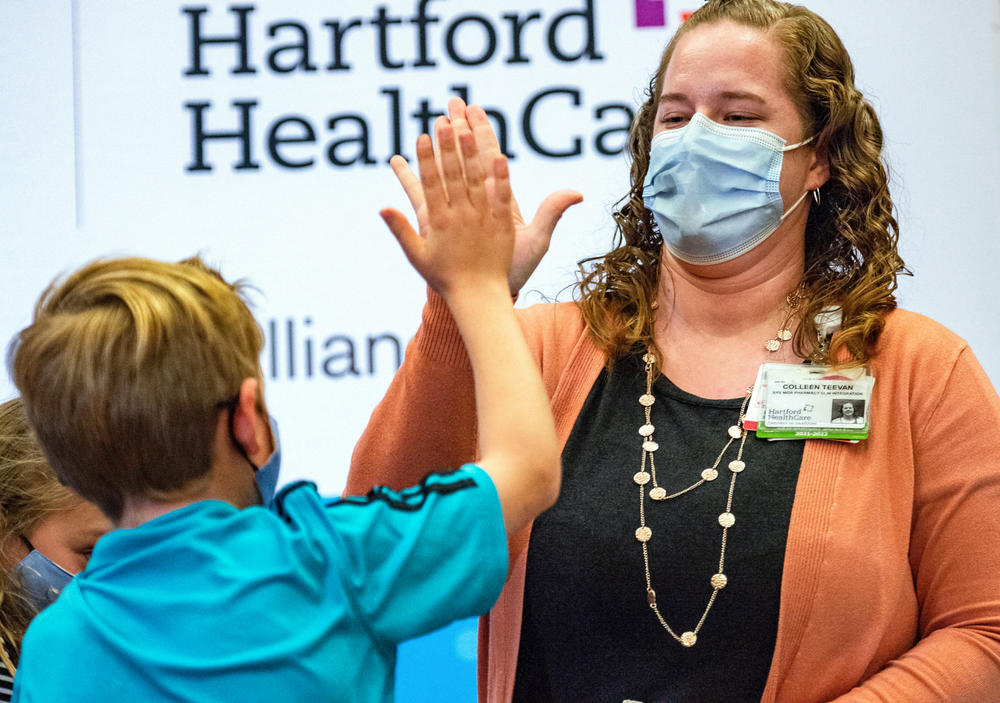 A 10-year-old child high fives Pharmacist Colleen Teevan after he received the Pfizer-BioNTech COVID-19 Vaccine for kids at Hartford Hospital in Hartford, Connecticut on November 2, 2021.