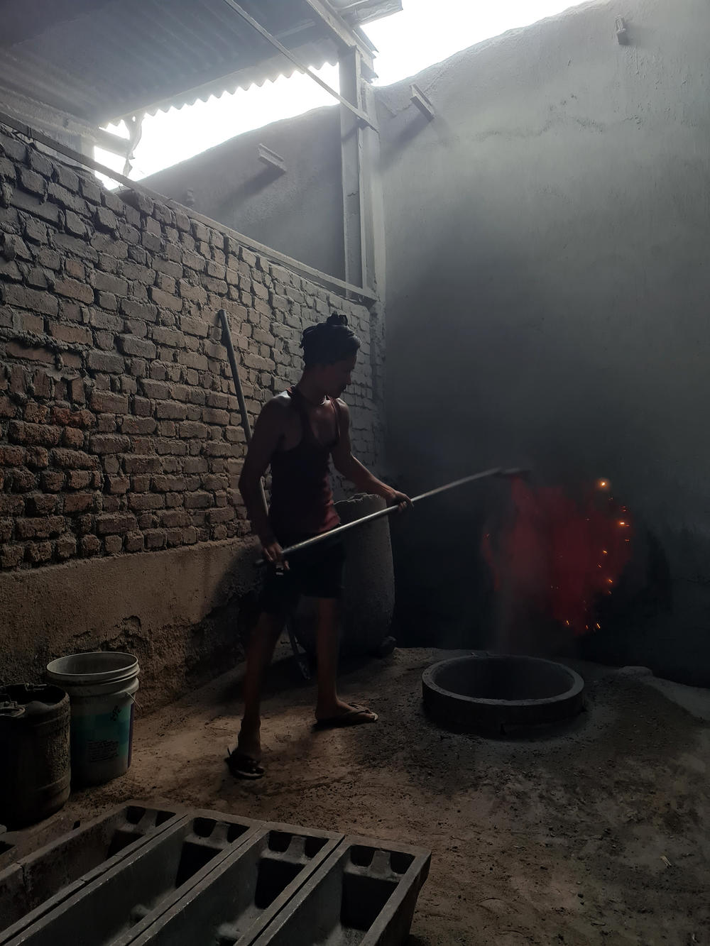 A worker melts aluminum over an open coal fire at a metal workshop around the corner from the Choudhary Coal Depot in Mumbai.