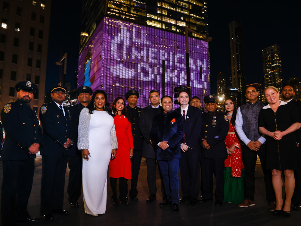 South Asian Engagement Foundation organizers and the NYPD colorguard stand in front of the digital mural celebrating Diwali shown on the World Trade Center.