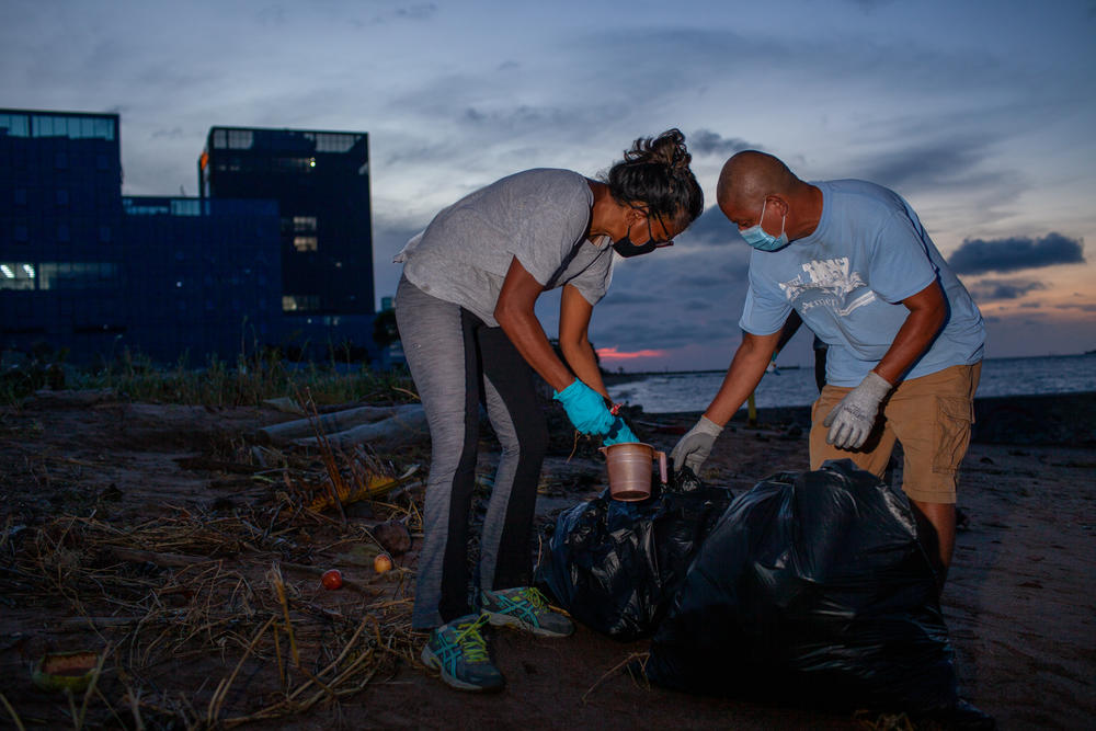 Syeada Manbodh and Bryan D'andrade, with the group Seawalls and Beyond, collect trash left on the beach. Other citizen-led environmental initiatives in Guyana are working to rebuild native mangrove forests, which act as natural sea defenses and prevent erosion.