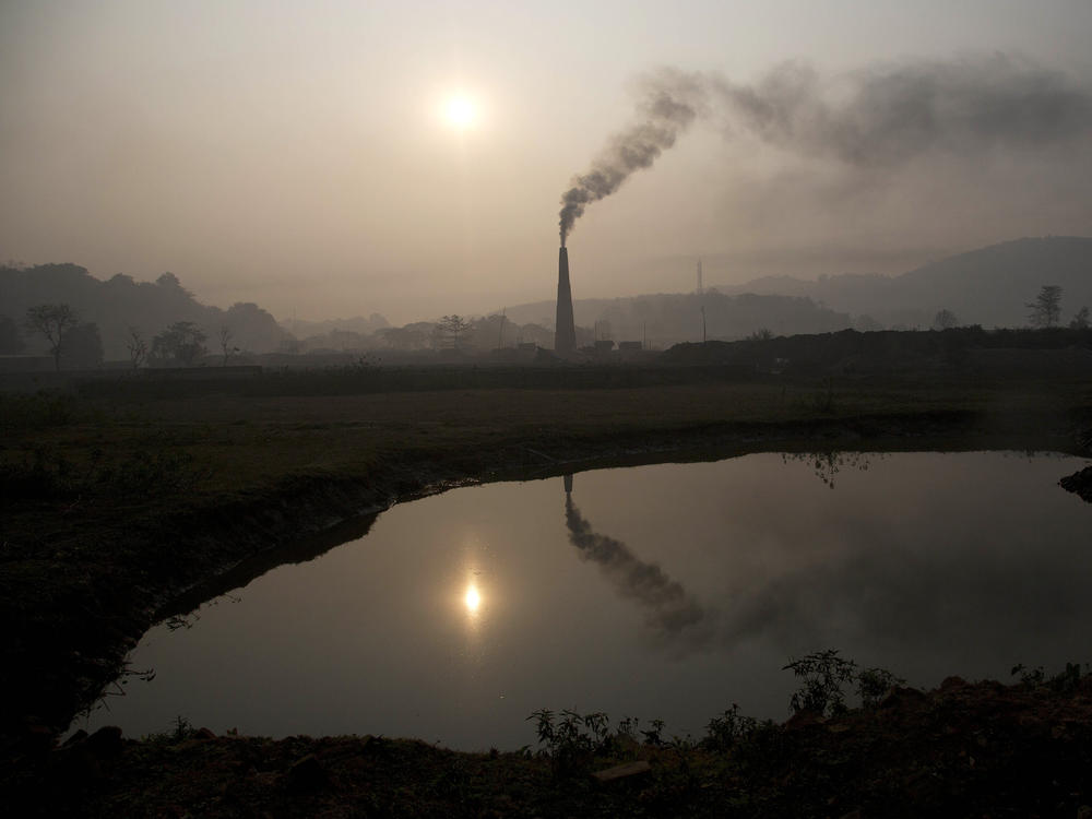 Smoke rises from a brick kiln on the outskirts of Gauhati, India, in 2015. India's pledge this week to reach net zero carbon emissions by 2070 factors into a new, more optimistic, analysis by the International Energy Agency on climate change goals.