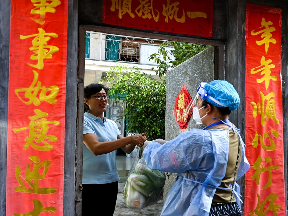 A community worker delivers daily necessities to a household during quarantine conditions in the southwestern Chinese city of Ruili. Residents have taken to social media to complain about what they describe as harsh lockdown measures brought on by China's zero COVID policy.