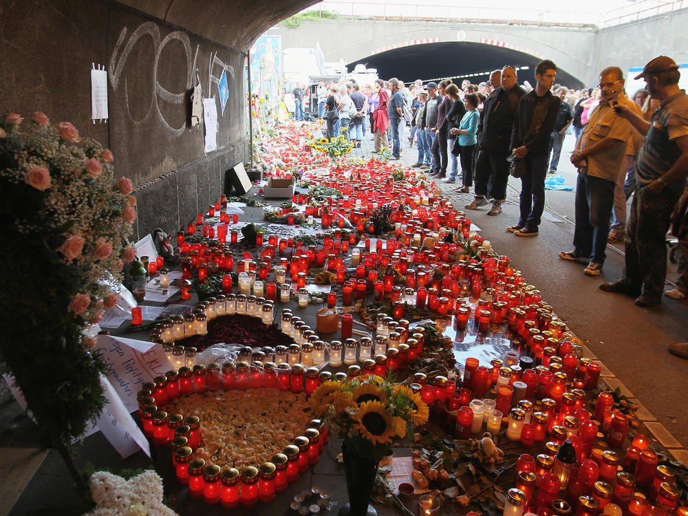 People mourn at the site of the Love Parade stampede on July 27, 2010 in Duisburg, Germany.