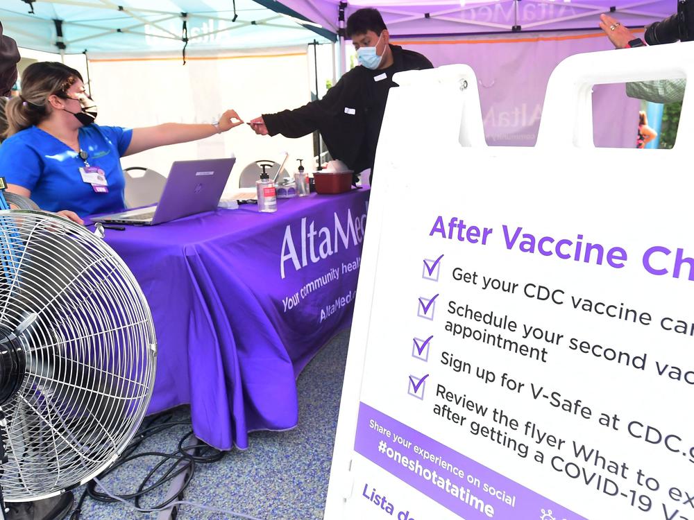 A nurse from AltaMed Health Services hands out the vaccine card to people after receiving their Covid-19 vaccine in Los Angeles, California on August 17, 2021.