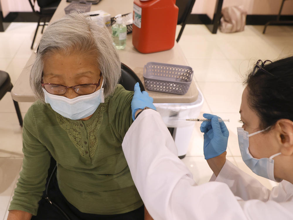 Safeway pharmacist Shahrzad Khoobyari administers a Pfizer-BioNTech COVID-19 booster shot to Chen Knifsend at a vaccination clinic in San Rafael, Calif., in October. The companies are seeking regulatory authorization to expand boosters to everyone 18 and older.