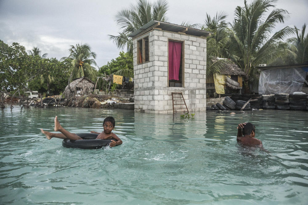 Children of Eita village swim in the area inundated by sea water during high tide.