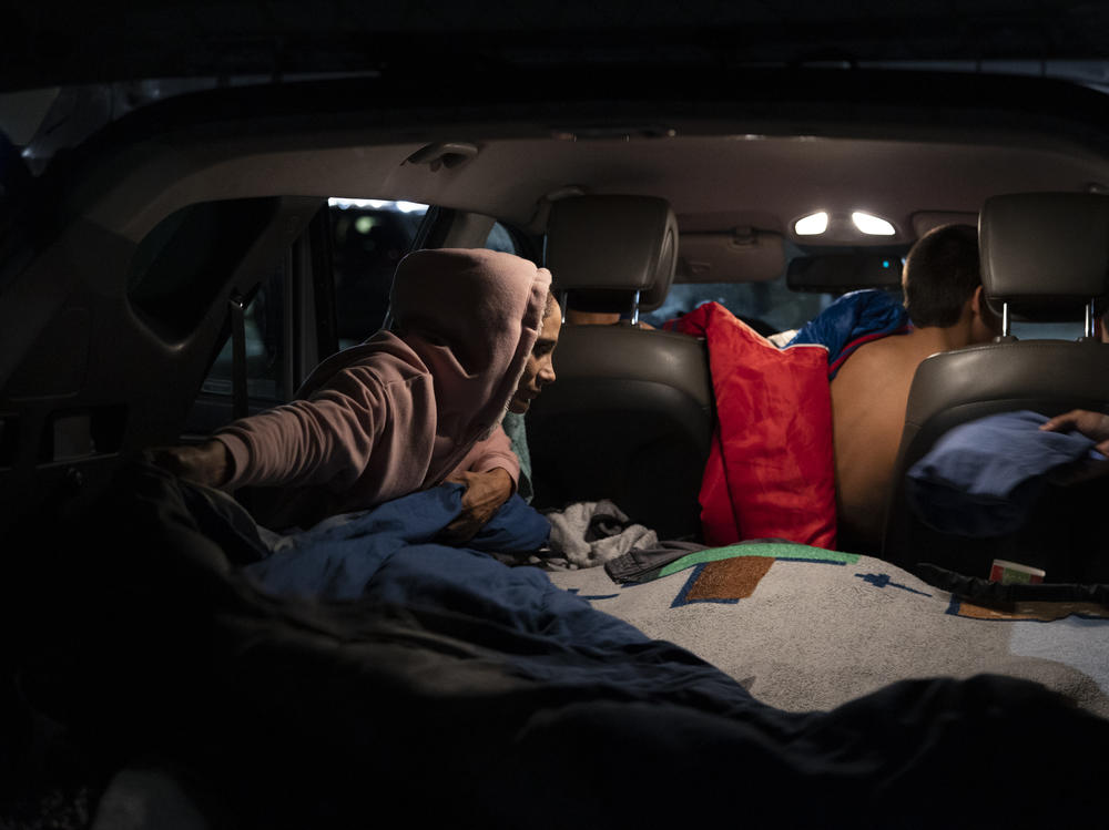 Veronica Vargas helps her children get ready for bed. The three boys sleep in the back of the SUV while Vargas and her partner, Alex, work the overnight shift.