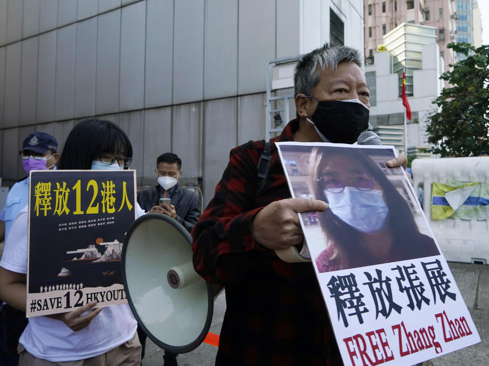 Pro-democracy activists (right) hold placards with the picture of Chinese citizen journalist Zhang Zhan as they march to the Chinese central government's liaison office in Hong Kong in Dec. 2020.
