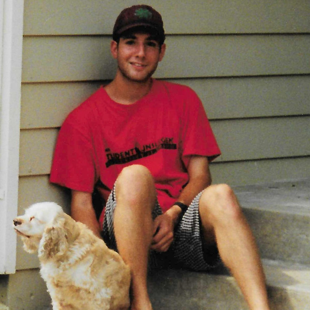 Kevin Aaron at the age of 19, relaxing with the family's dog, Sprite, at his childhood home in Overland Park, Kansas. His t-shirt reads 