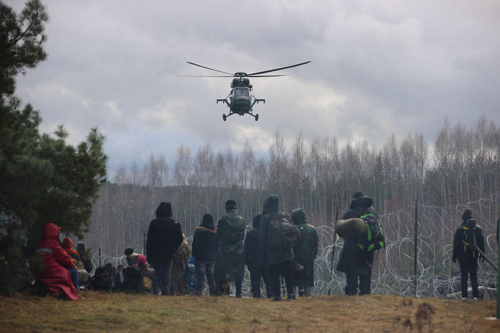 Migrants at the Belarusian-Polish border in the Grodno region, in Belarus, watch a helicopter overhead on Nov. 8.