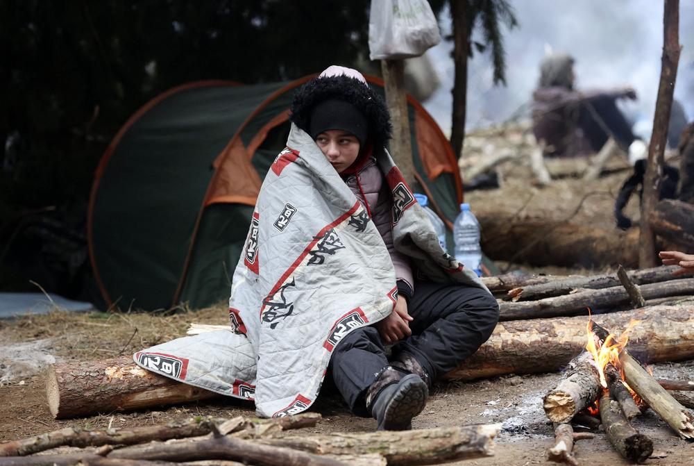 A migrant sits in front of a fire in a camp near the Belarusian-Polish border in the Grodno region, in Belarus, Sunday.