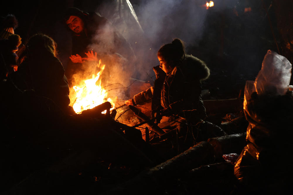 Migrants warm themselves by a fire in a camp on the Belarusian-Polish border in the Grodno region, in Belarus, on Sunday. Some migrants say they were beaten and frightened with dogs by Belarusian soldiers.