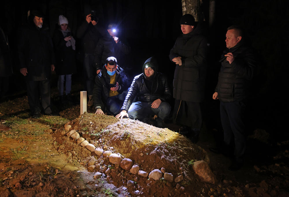 Mourners place their hands on the grave of Ahmad al-Hasan, 19, during his burial at the Muslim cemetery of the local Tatar community on Monday in Bohoniki, Poland. Hasan, from Homs, Syria, drowned in the Bug River while attempting to cross from Belarus into Poland on Oct. 19. There are reports of at least 11 migrants having died in recent months while trying get into Poland from Belarus.