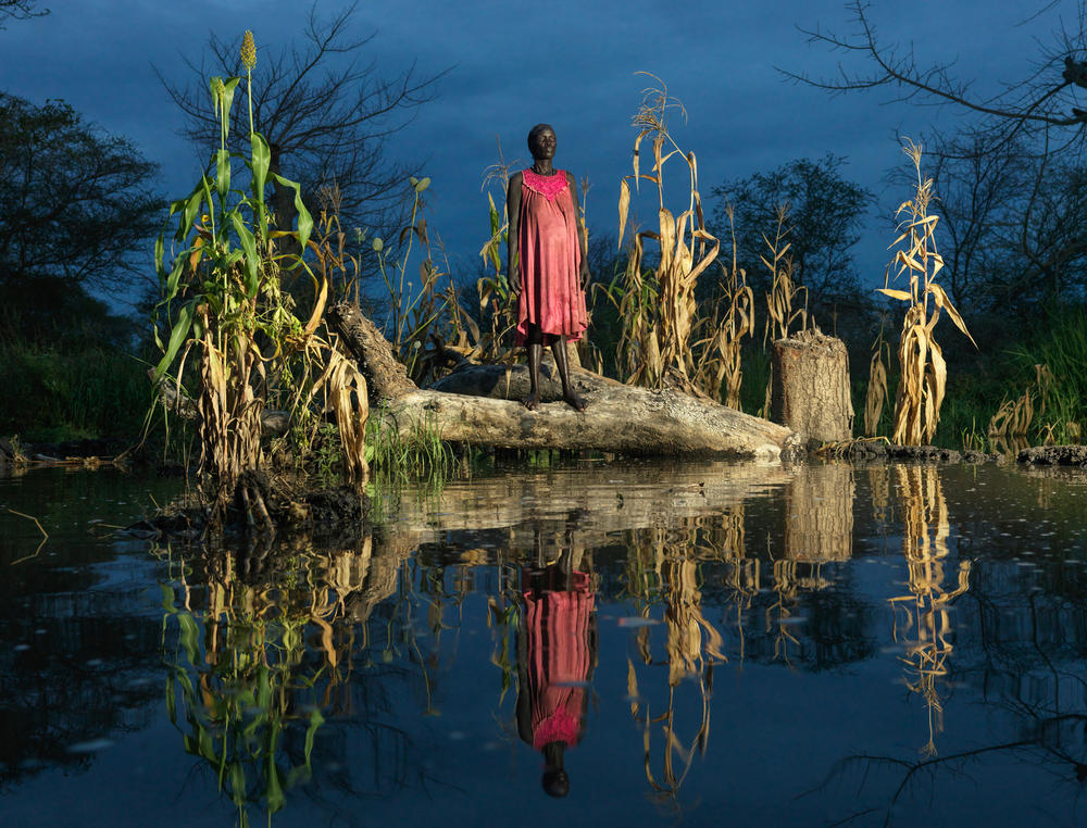 Nyadiang Gak, 50, stands beside her flooded crops. 