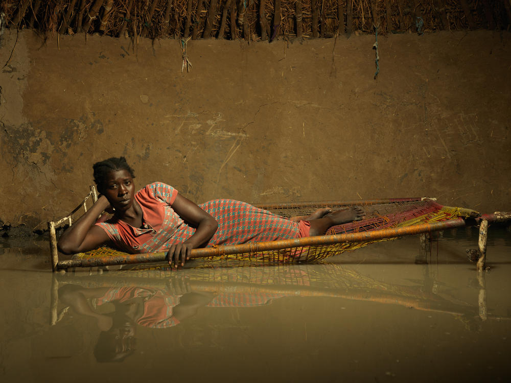Nyapini Yiel, 23, lies in her bed surrounded by floodwater. 