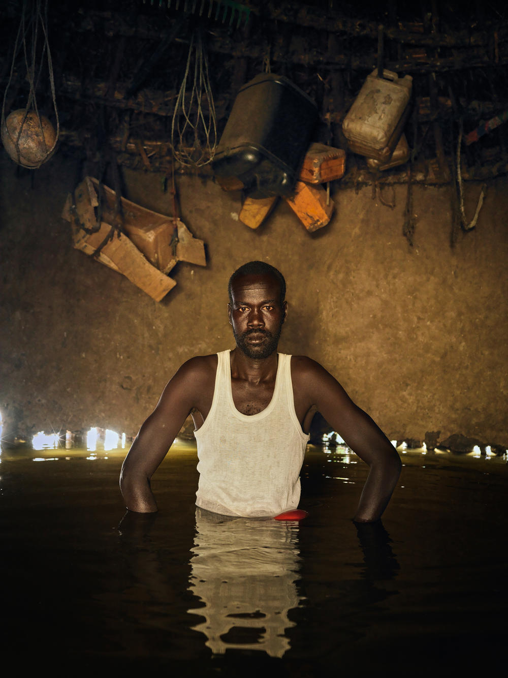 Stephen Koang stands inside his destroyed home. He and his family are now sleeping on the ground of his neighbor's compound, whose dike is still resisting the water. 