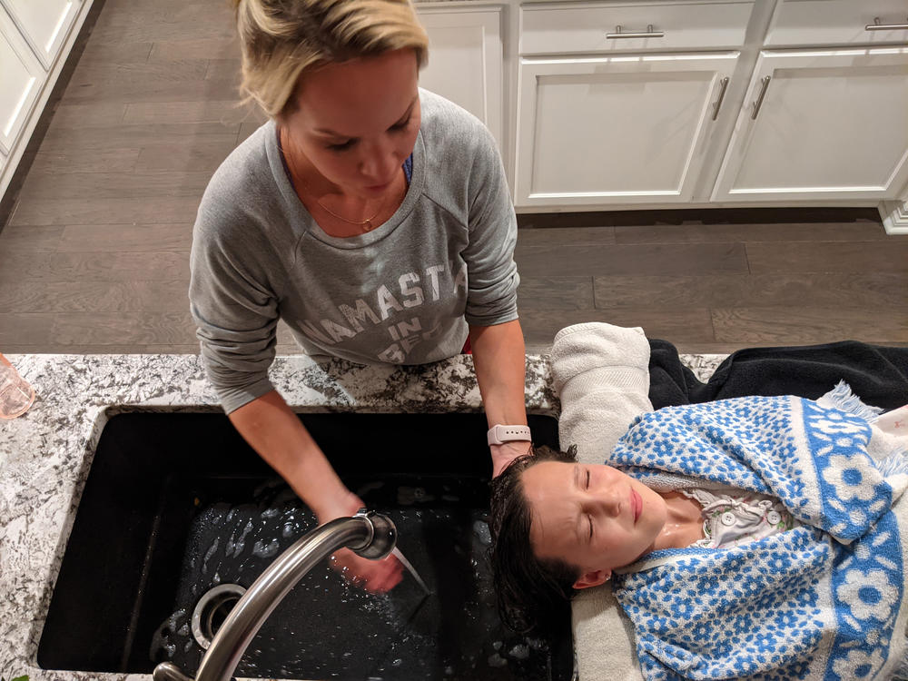Paris Marker washes olive oil out of her daughter's hair after LiceDoctors technician Linda Holmes finished combing through it, looking for lice and nits — the eggs of the parasitic insects. The Markers paid more than $200 for Holmes to check and delouse everyone in the four-person household in Parker, Colo.