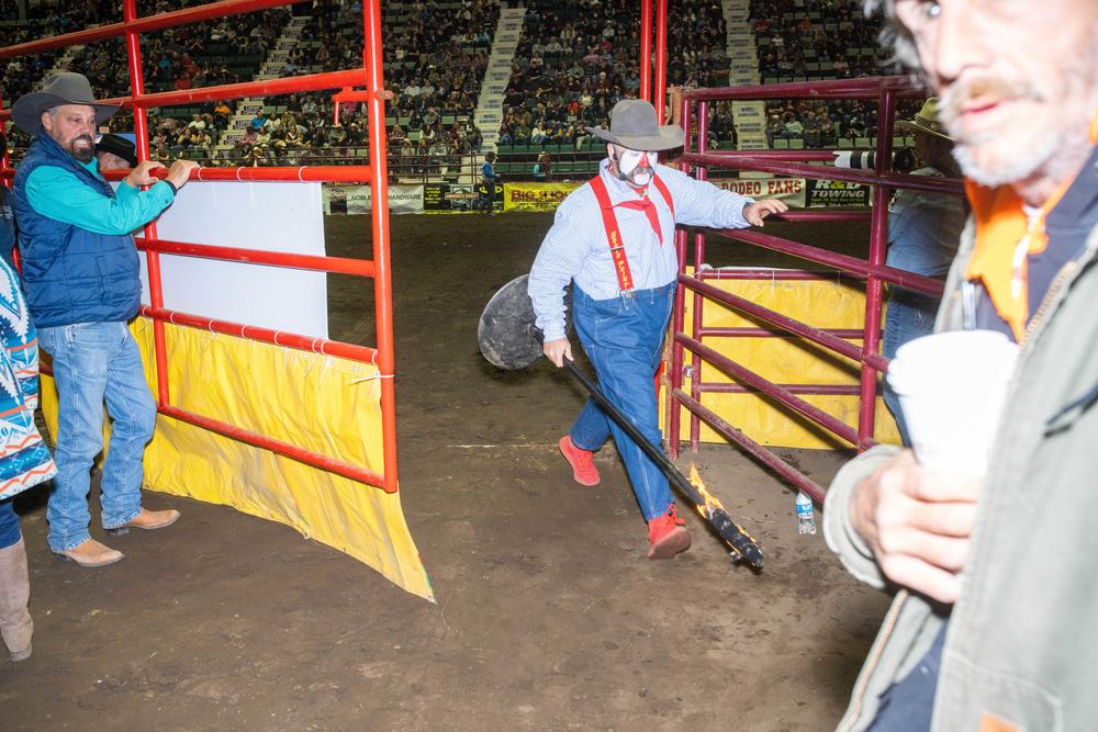Rodeo Clown Rob Gann helps move fire props for trick rider.