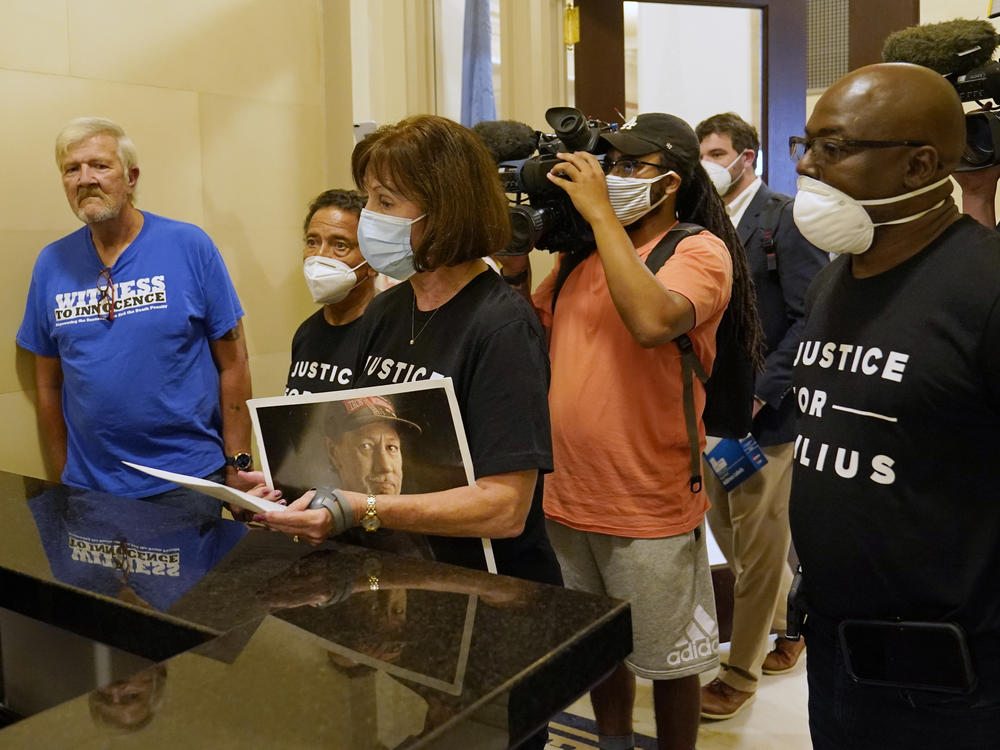 Nancy Vollertsen — with a photo of her brother, Greg Wilhoit, who spent five years on death row before being exonerated — holds a letter urging a speedy commutation hearing for Julius Jones, earlier this fall in Oklahoma City. She was joined by exonerated former death row inmates (from left) Gary Drinkard, Juan Melendez and Herman Lindsey.