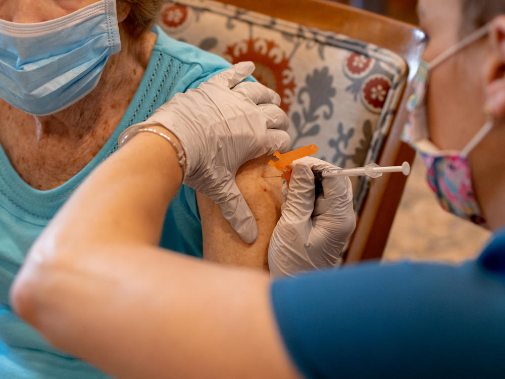 A health care worker administers a third dose of the Pfizer-BioNTech COVID-19 vaccine at a senior living facility in Worcester, Pa., in August.