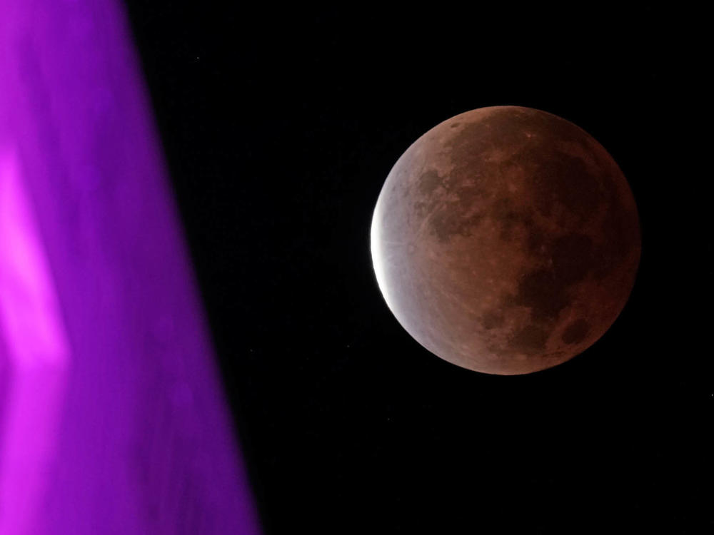 The earth's shadow covers the full moon during a partial lunar eclipse as it sets beyond city hall, Friday, Nov. 19, in downtown Kansas City, Mo.