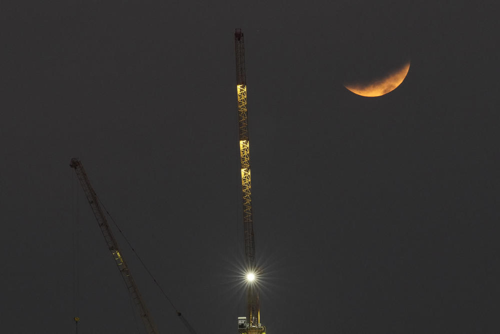 A partial lunar eclipse is seen behind a crane in Manila, Philippines on Friday.