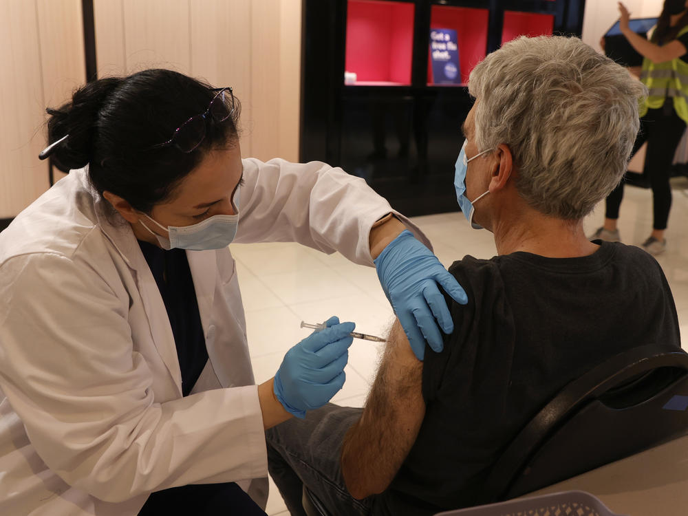 Safeway pharmacist Shahrzad Khoobyari administers a Pfizer-BioNTech COVID-19 booster shot into the arm of Norman Solomon in San Rafael, Calif., in October.