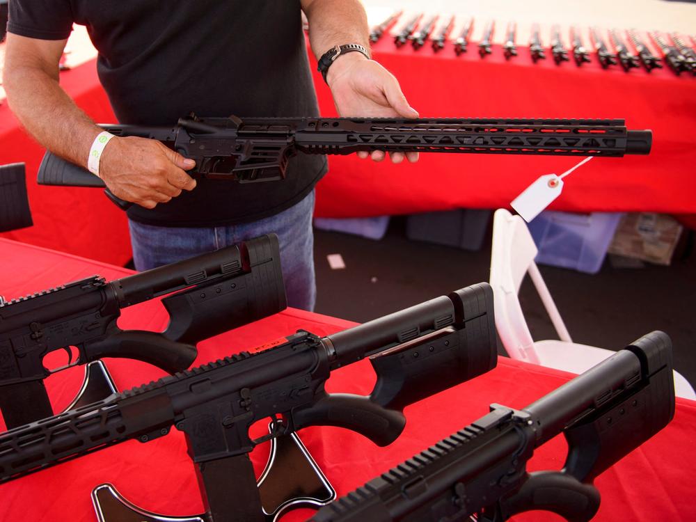 A clerk shows a customer an AR-15 style rifle at a gun show in Costa Mesa, Calif. in June 2021. Gun sales increased in the U.S, following COVID-19 pandemic lockdowns.