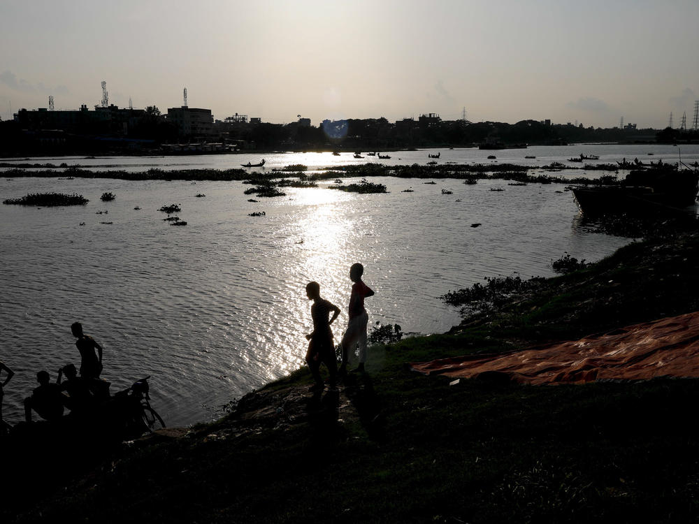 Two boys stand at the edge of the Buriganga River in Dhaka, Bangladesh, in July. A recent study finds that globally, boys and young men made up two-thirds of all deaths among young people in 2019.