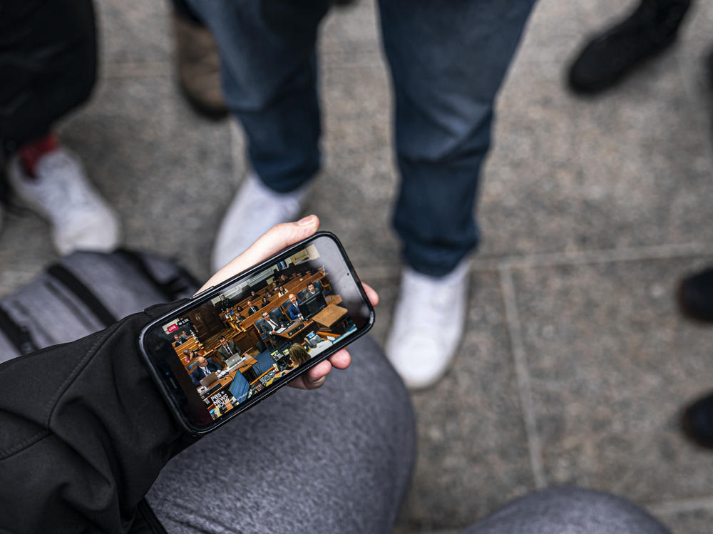 Activists calling for the conviction of Kyle Rittenhouse watch the trial on a phone in front of the Kenosha County Courthouse while the jury deliberates the Rittenhouse verdict on Wednesday in Kenosha, Wisc.